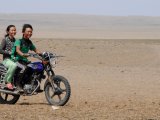 Para młodych Mongołów jadących motocyklem po pustynnym terenie, symbol nowoczesności w tradycyjnym krajobrazie stepu. #20